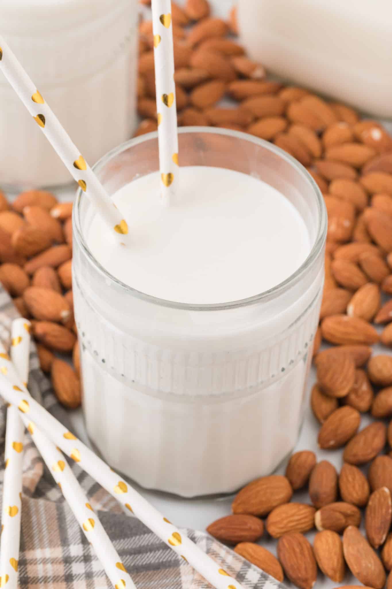 leche de almendras sobre una mesa de cristal rodeada de almendras.