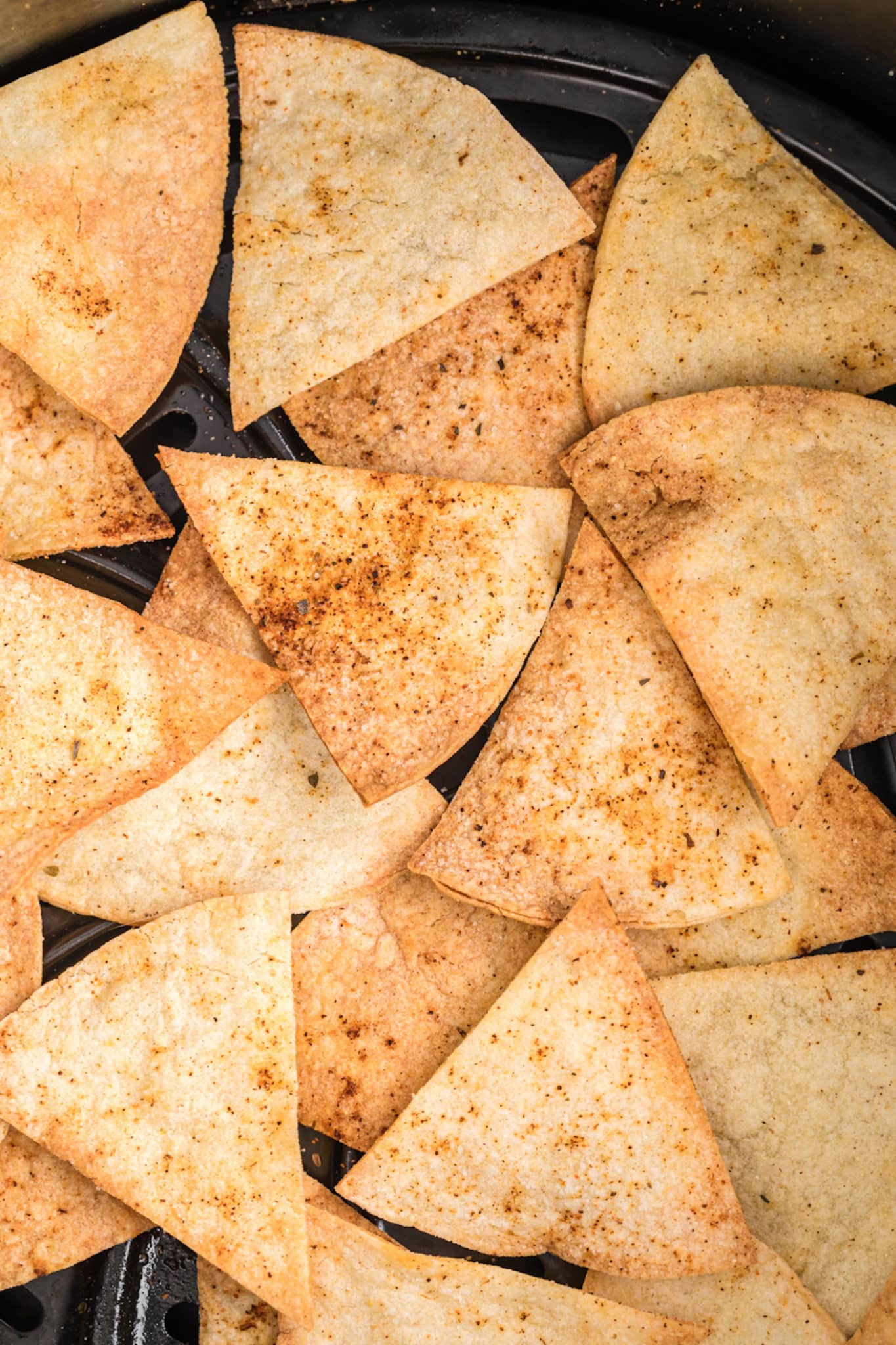 Primer plano de chips de tortilla de maíz caseros en una canasta de freidora.