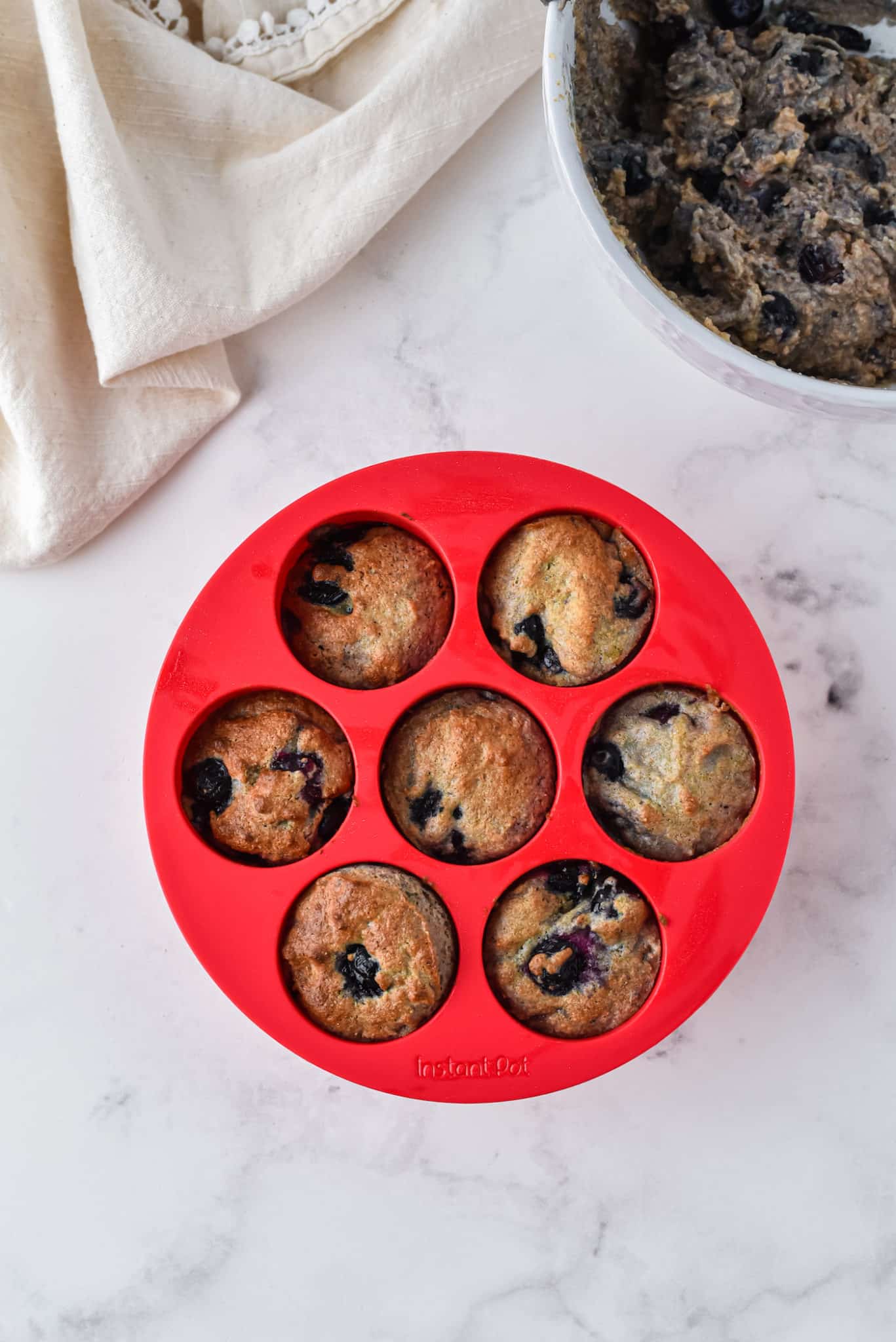 Un molde de silicona para muffins rojo con 6 muffins de arándanos horneados.