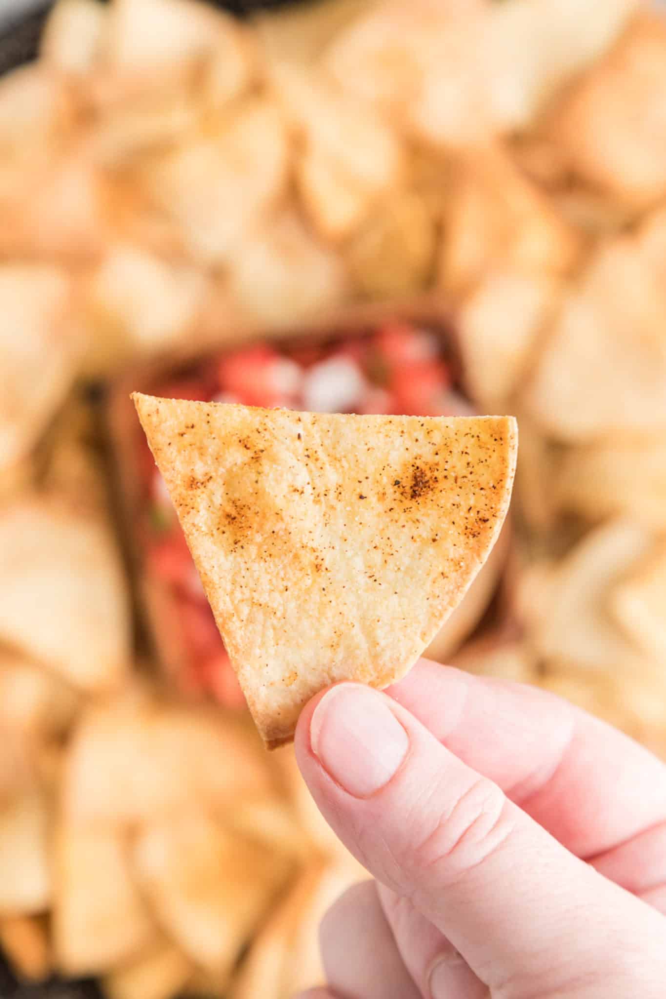 mano sosteniendo un chip de tortilla de freidora casero listo para comer