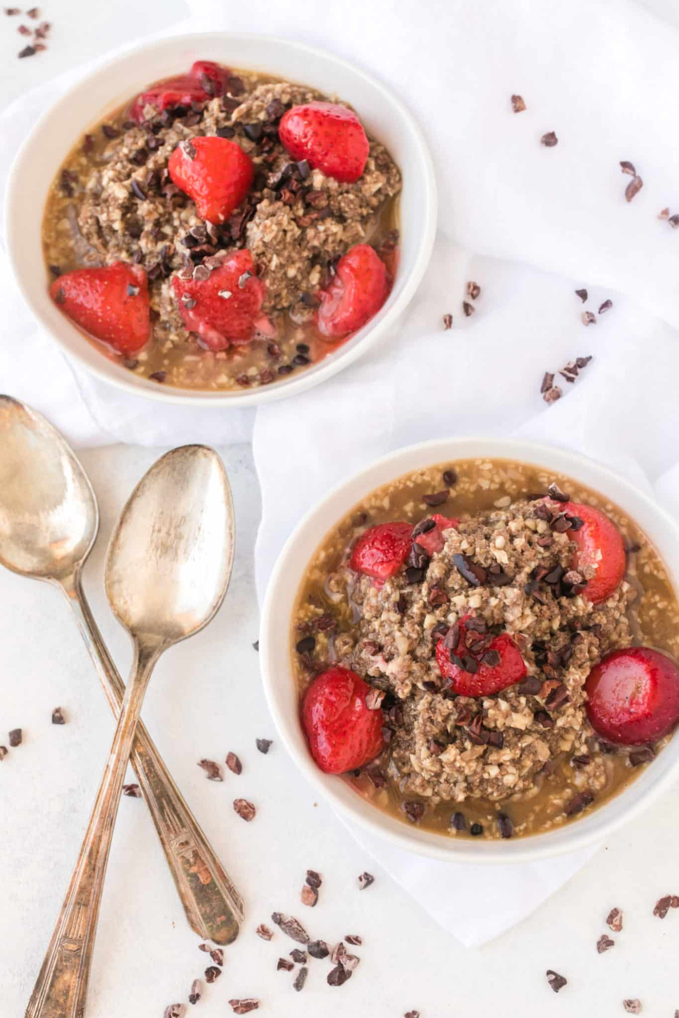 dos tazones de avena de coliflor con nibs de cacao y fresas.