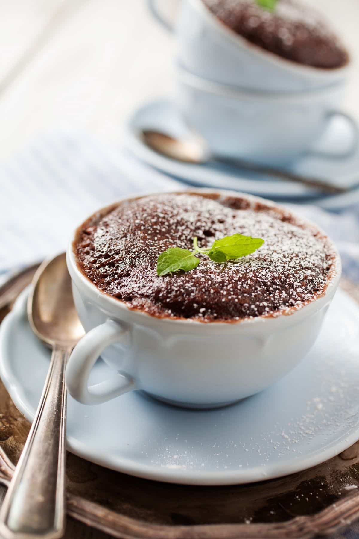 pastel de taza de chocolate en la mesa con azúcar en polvo encima.