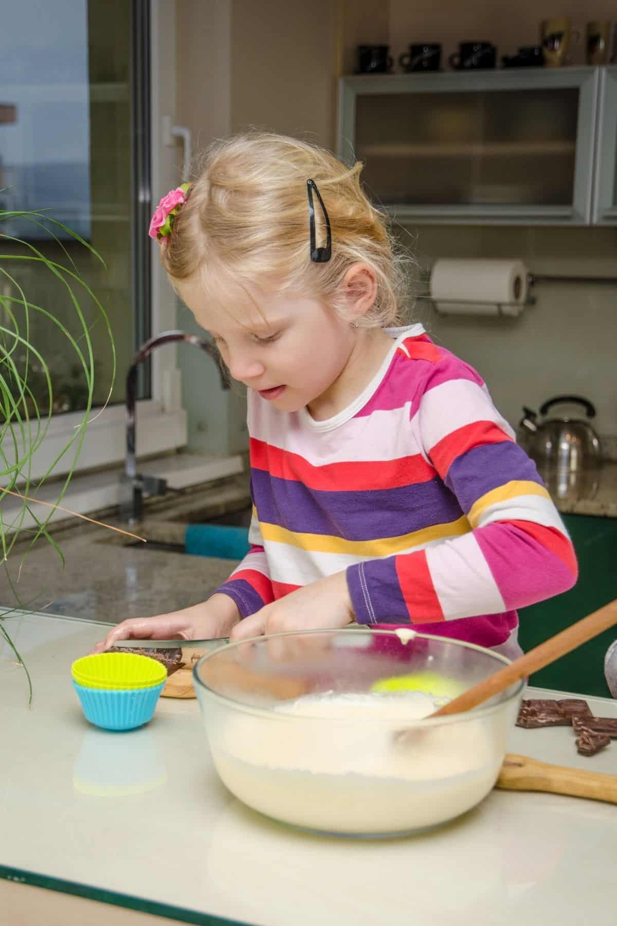 niña haciendo panecillos en la cocina.