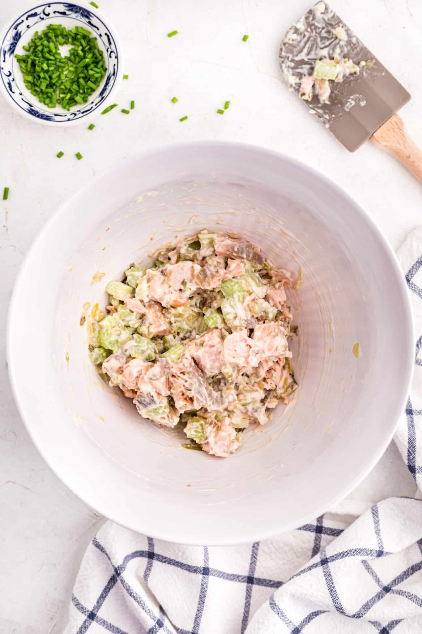 Ensalada de salmón mezclada con mayonesa en un tazón blanco grande.