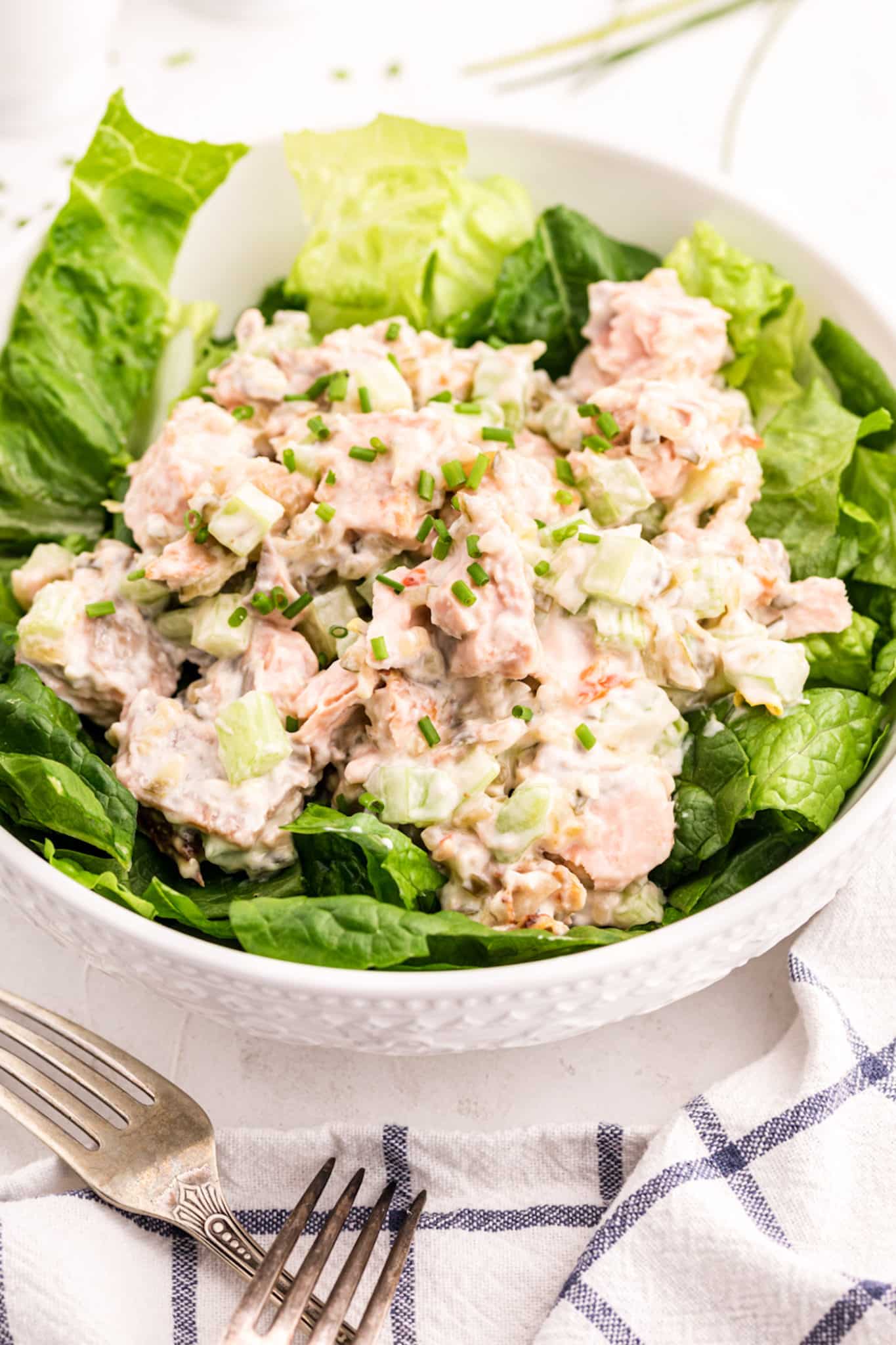 Ensalada de salmón con apio y mayonesa con lechuga en un tazón blanco grande.