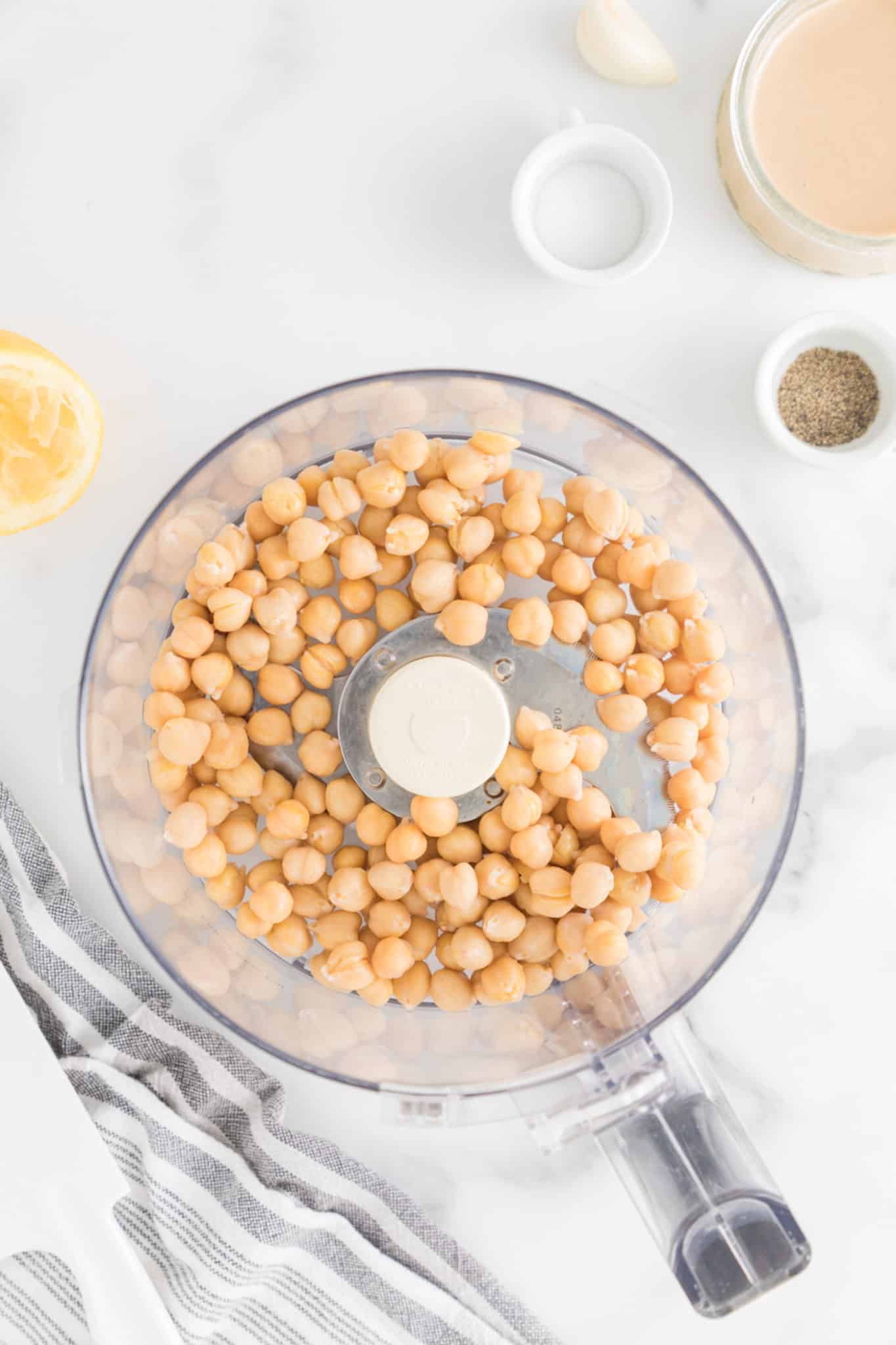 Garbanzos enlatados, escurridos y enjuagados, en el recipiente de un procesador de alimentos.