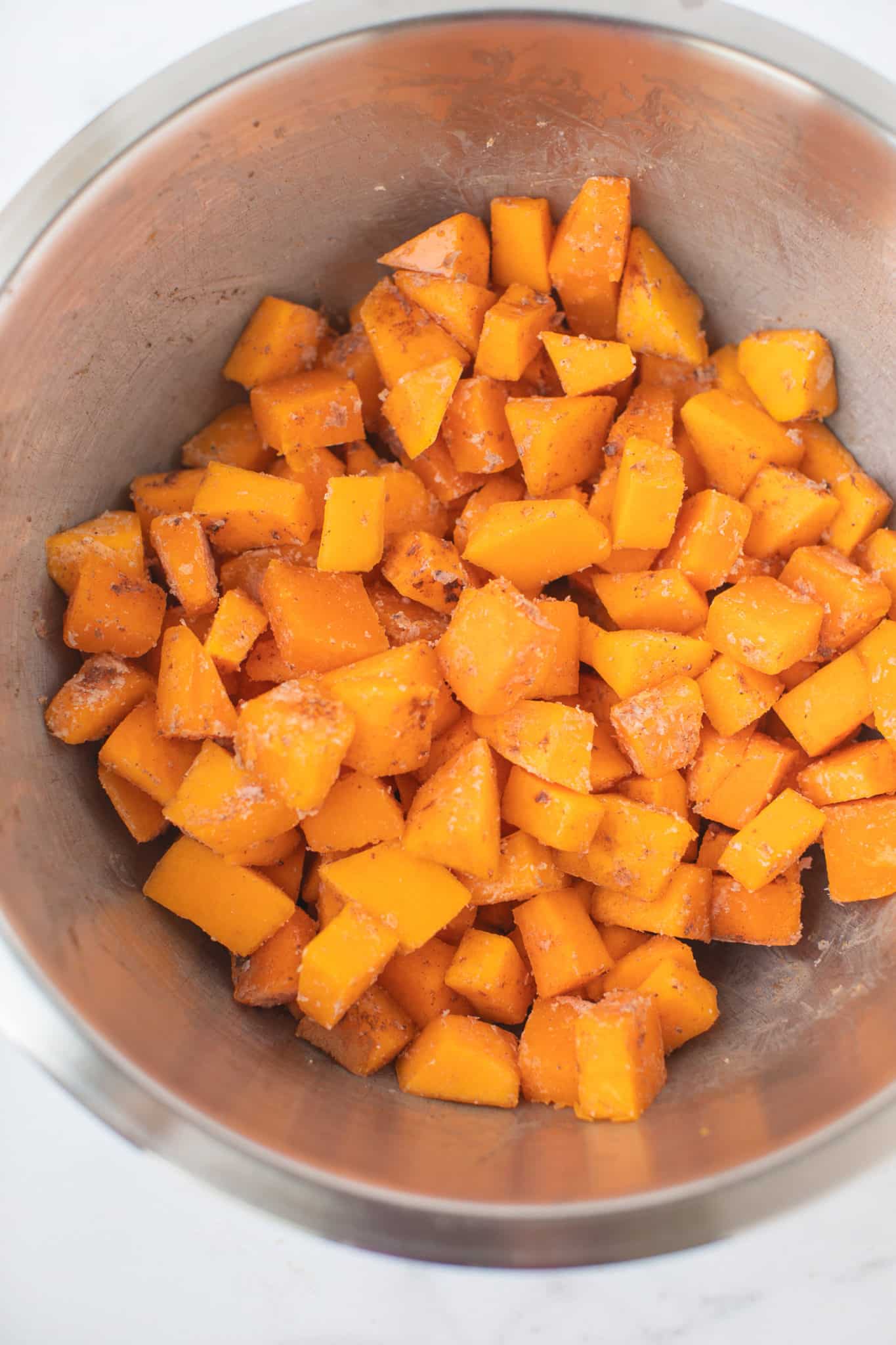 tazón de calabaza en cubos con aceite de coco listo para hornear