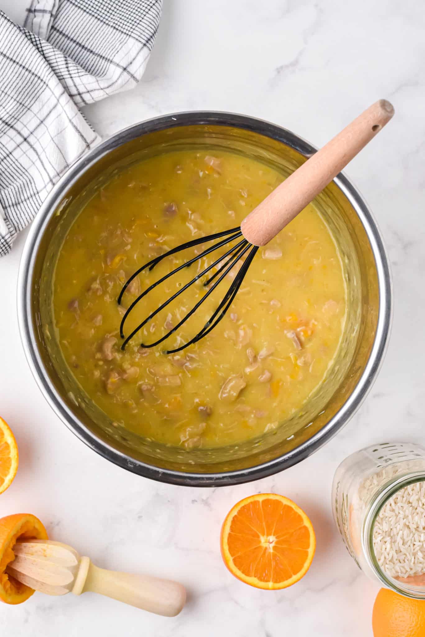 Un batidor en la olla instantánea llena de pollo a la naranja.