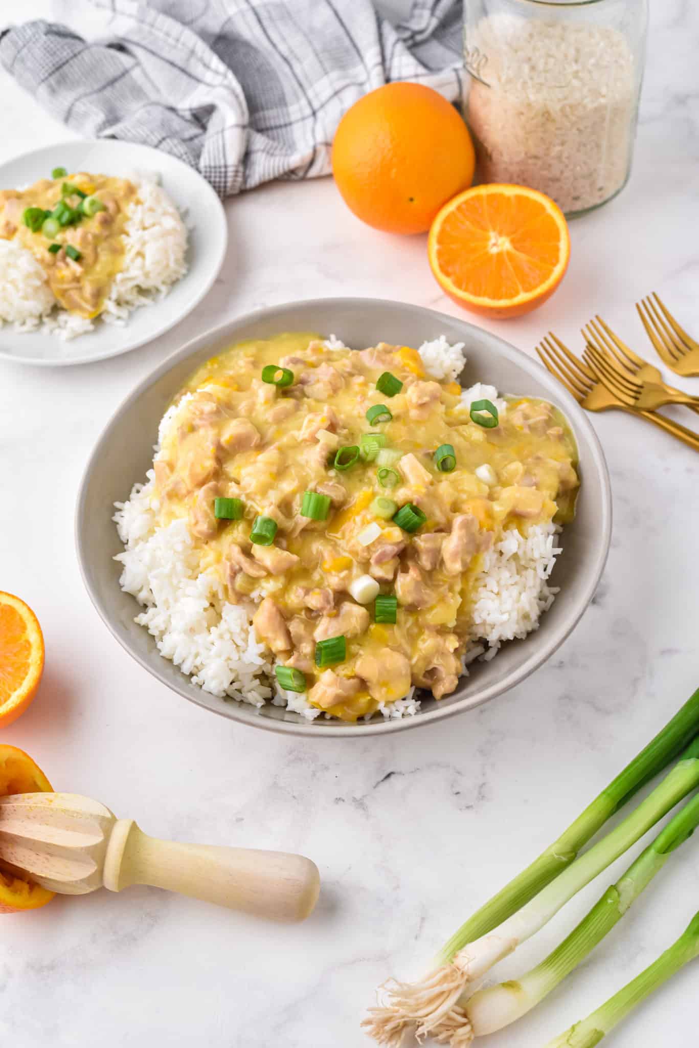 Pollo instantáneo a la naranja sobre arroz blanco en un tazón gris grande.