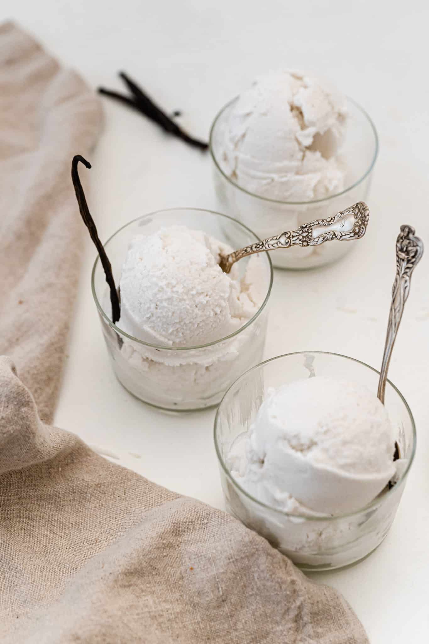 Tres tazones de vidrio pequeños de helado de vainilla sin batir.