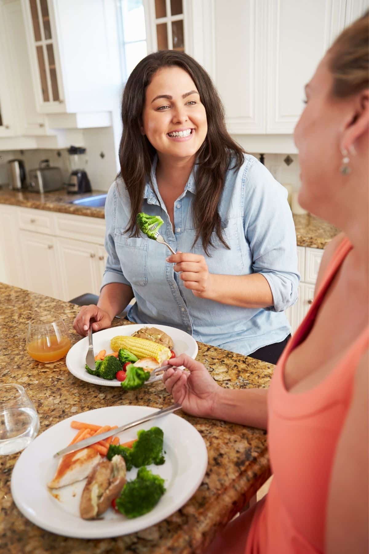 dos mujeres comiendo juntas en una cocina.