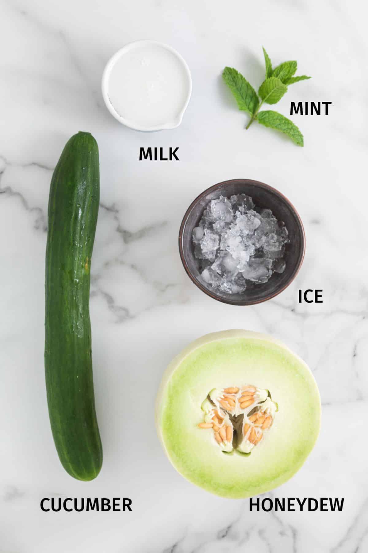 Ingredientes para hacer el batido de pepino Honeydew sobre una superficie blanca.