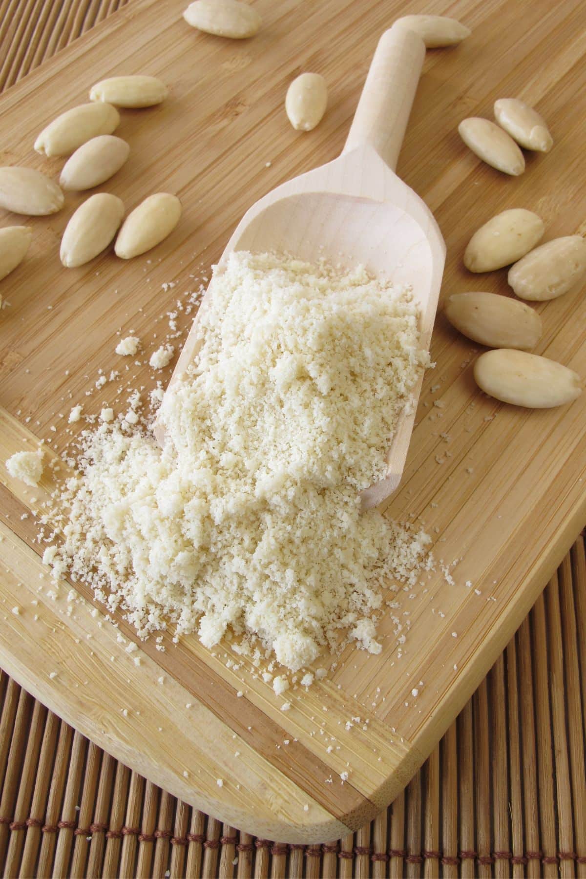 Cucharada de harina de almendras con almendras sobre estera de bambú.